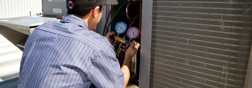 HVAC technician servicing a condenser unit in McCandless